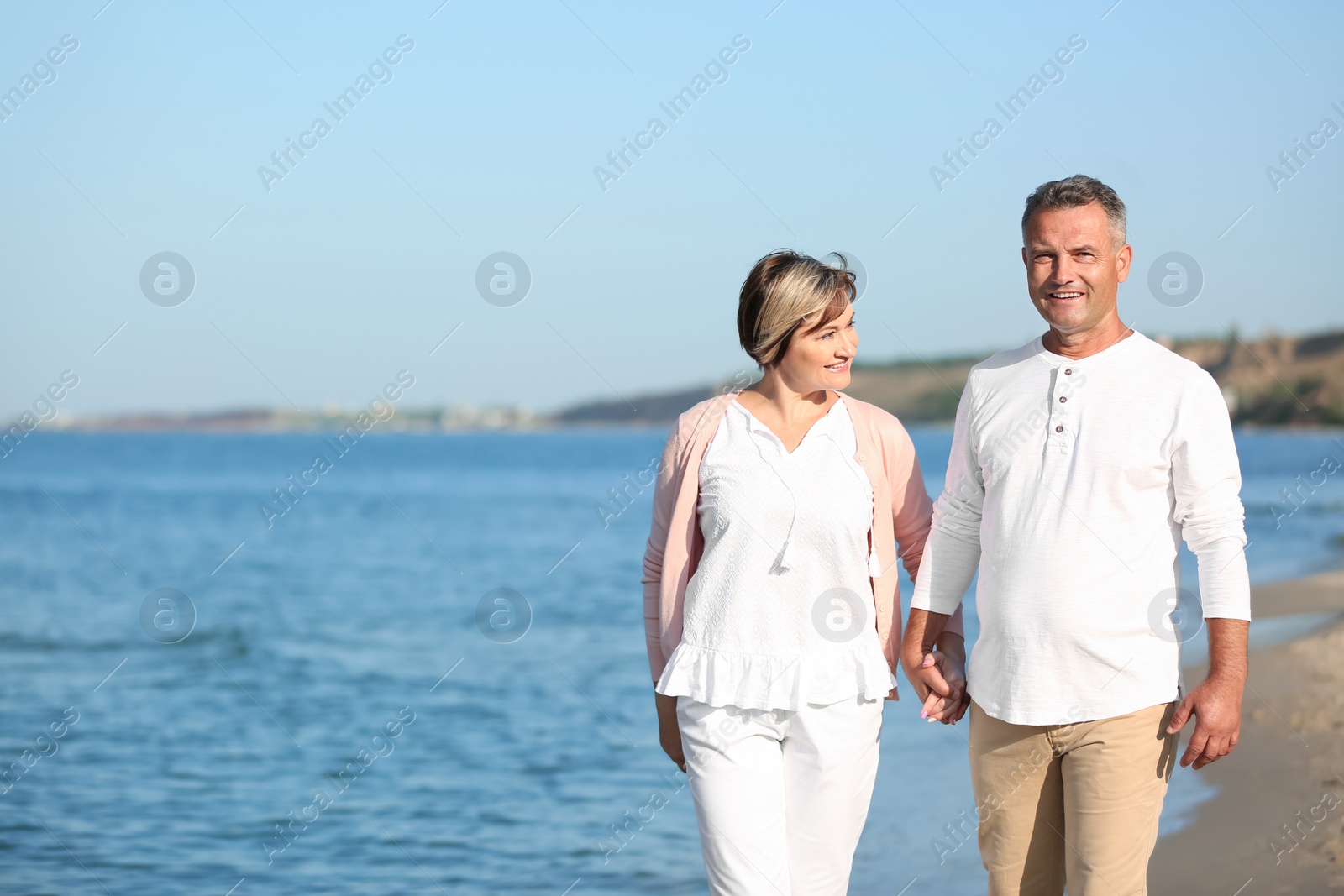 Photo of Happy mature couple walking at beach on sunny day