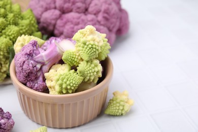 Photo of Various cauliflower cabbages on white tiled table, space for text