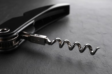 Photo of One corkscrew (sommelier knife) on grey textured table, closeup