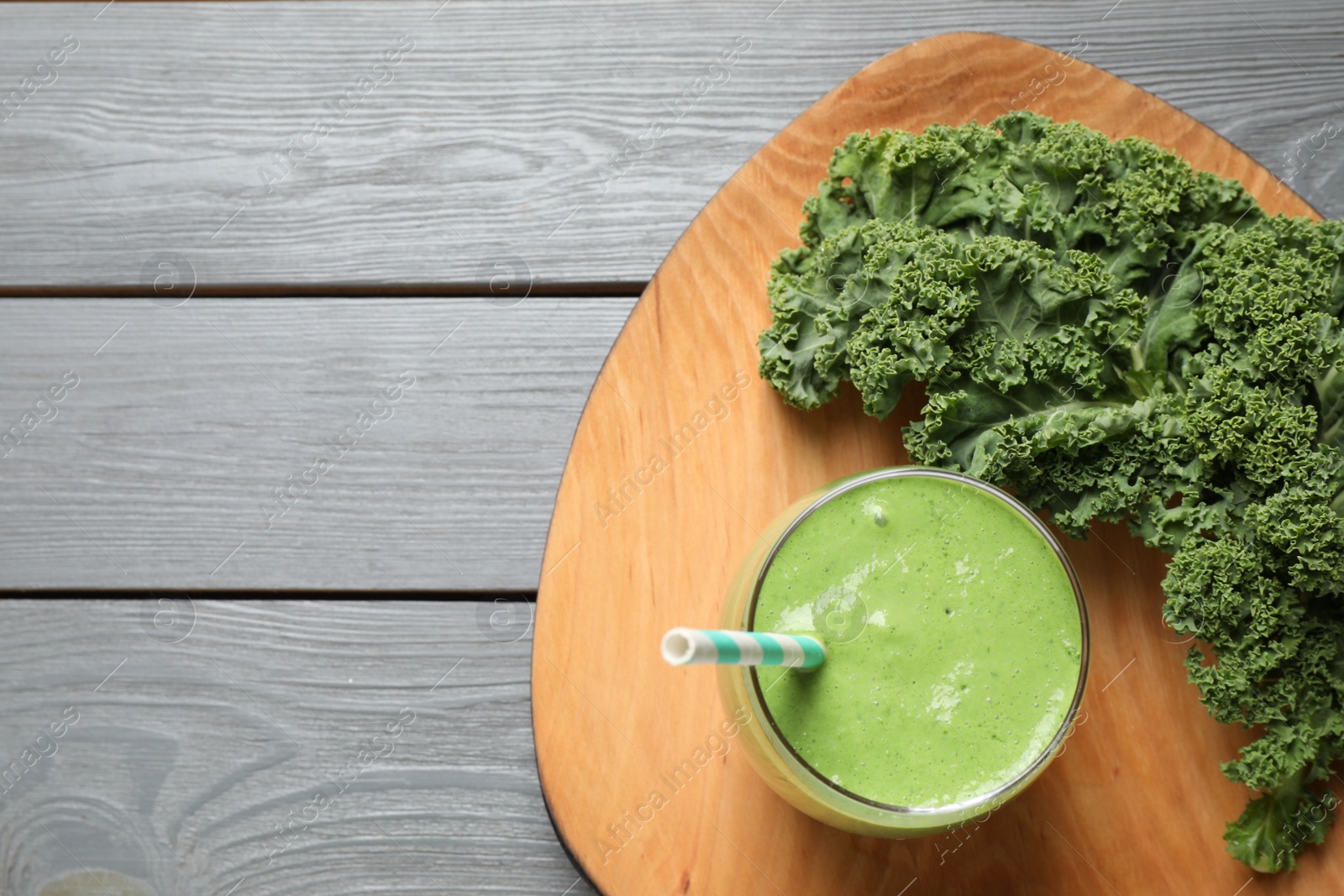 Photo of Tasty kale smoothie on light grey wooden table, flat lay. Space for text