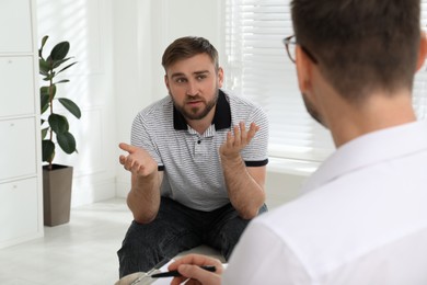 Photo of Psychotherapist working with drug addicted young man indoors