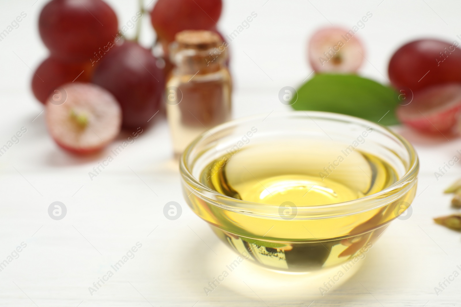 Photo of Natural grape seed oil on white wooden table. Organic cosmetic