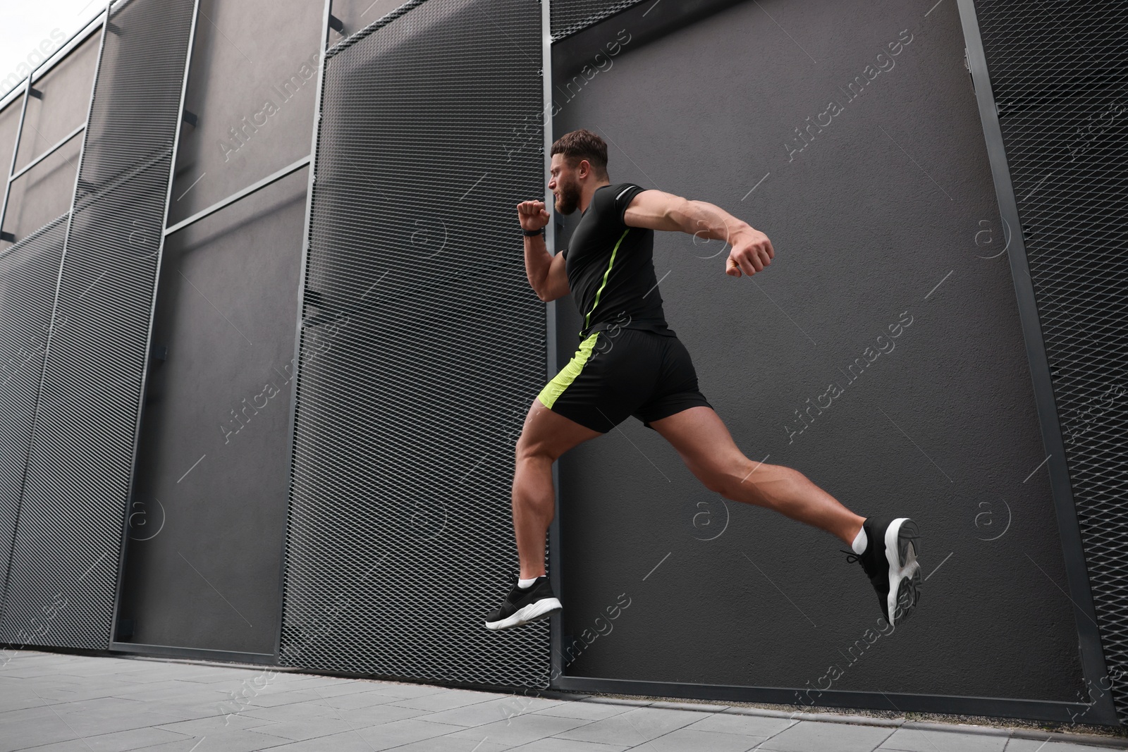 Photo of Man running near building outdoors, low angle view. Space for text