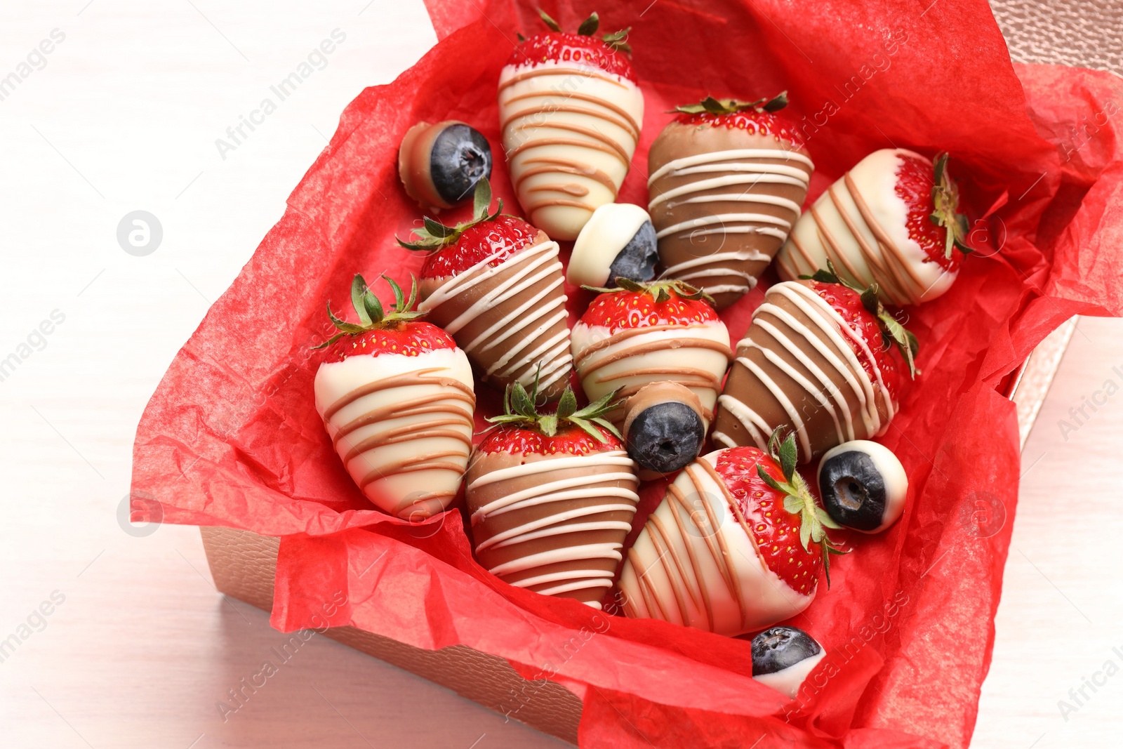 Photo of Box with delicious chocolate covered strawberries and blueberries on white table