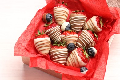 Photo of Box with delicious chocolate covered strawberries and blueberries on white table