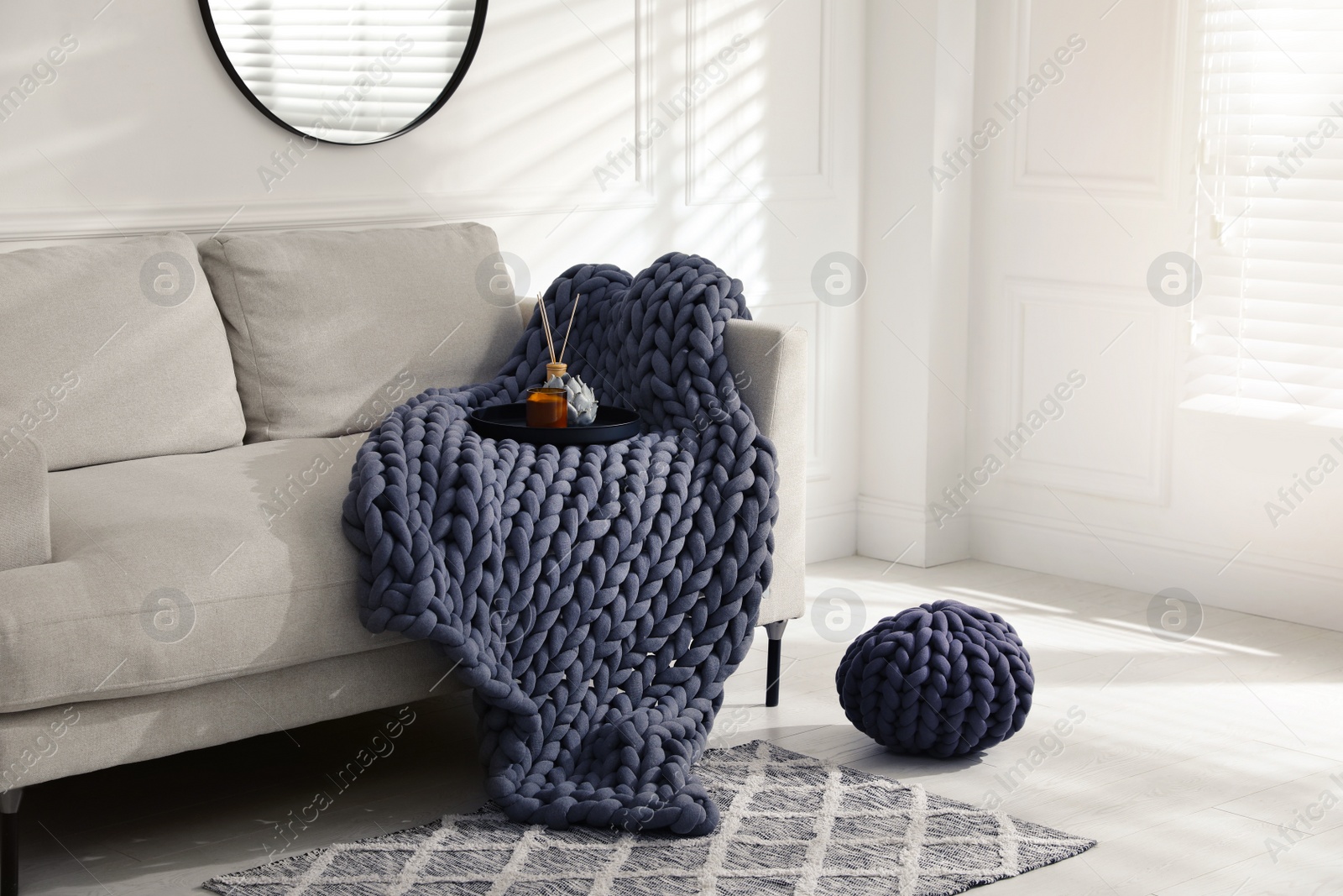 Photo of Soft chunky knit blanket on sofa in living room. Interior design