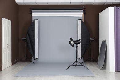 Photo of Grey photo background and professional lighting equipment in studio