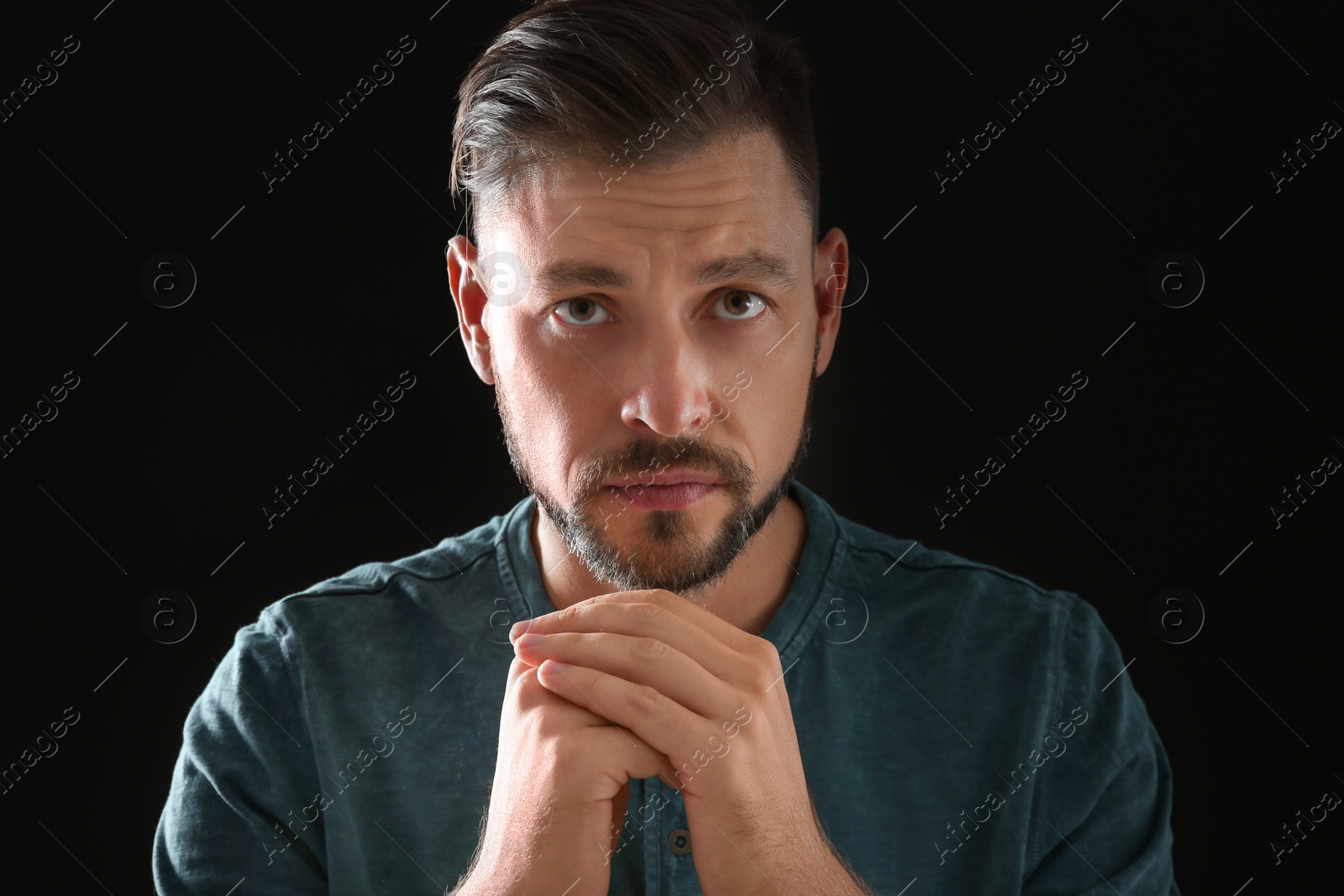 Photo of Man with hands clasped together for prayer on black background