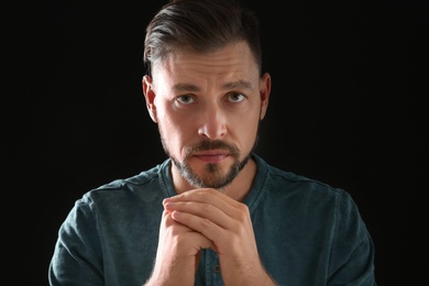 Photo of Man with hands clasped together for prayer on black background