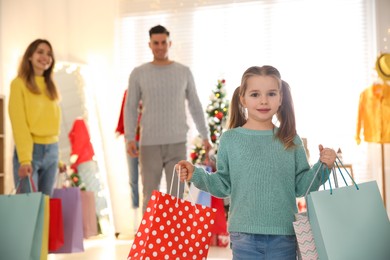 Little girl with bags near her parents in store. Family Christmas shopping