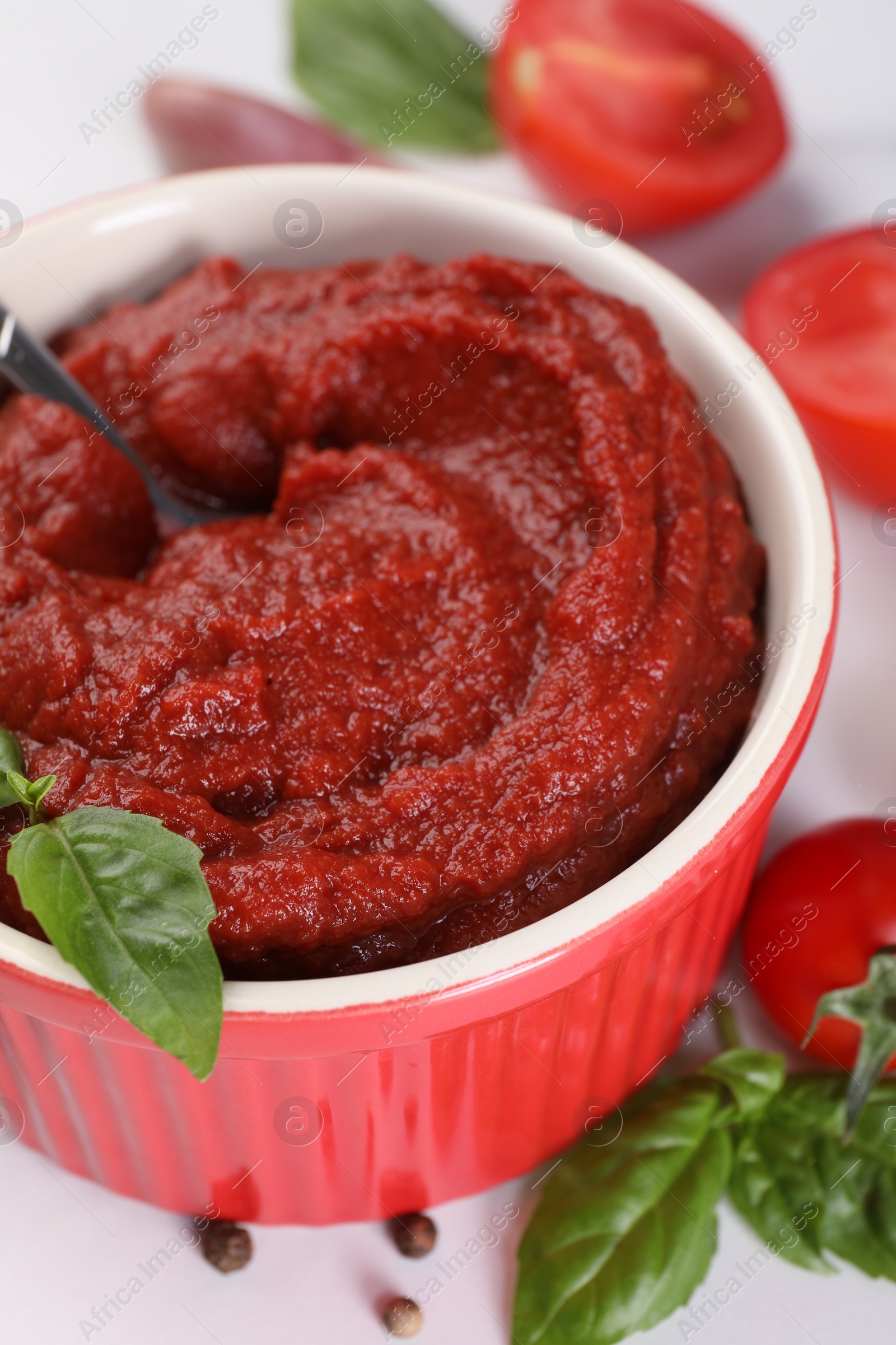 Photo of Tasty tomato paste in bowl on white table, closeup