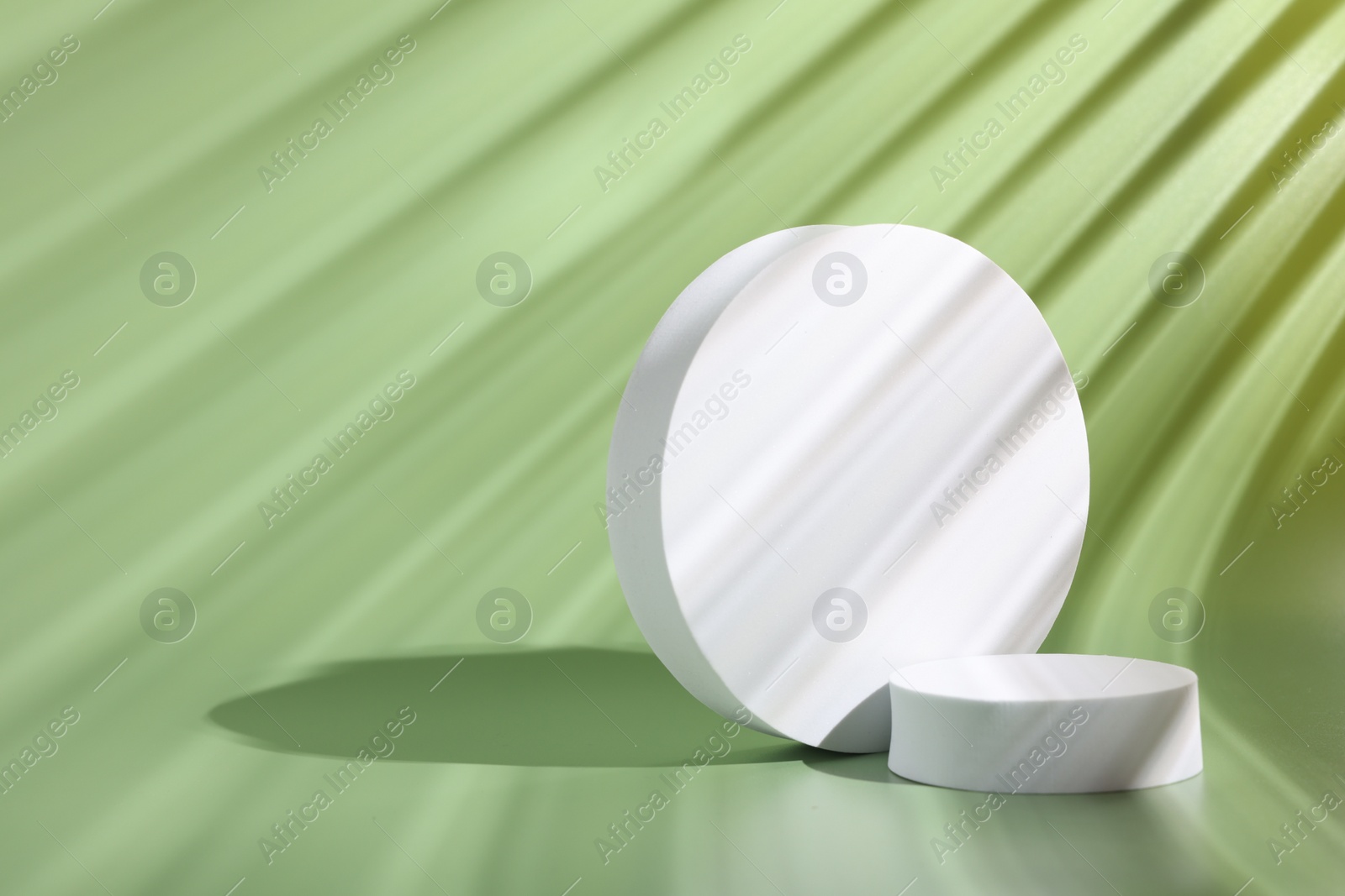 Photo of Scene with podium for product presentation. Round figures on pale light green background, space for text