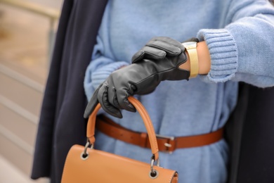 Photo of Young woman with stylish black leather gloves and bag outdoors, closeup