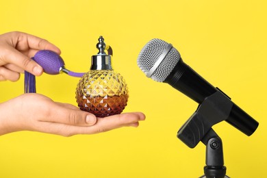 Photo of Woman making ASMR sounds with microphone and perfume on yellow background, closeup