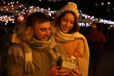 Photo of Happy couple with gift box at Christmas fair