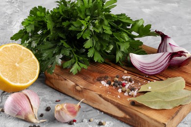 Bunch of fresh parsley, lemon, onion, garlic and spices on grey textured table
