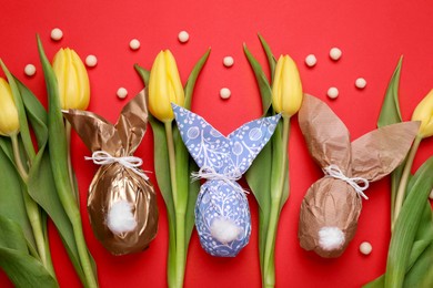 Photo of Flat lay composition with Easter bunnies made of paper and eggs on red background