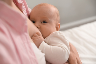 Photo of Young woman breast feeding her little baby, closeup