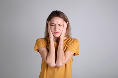 Portrait of stressed young woman on grey background