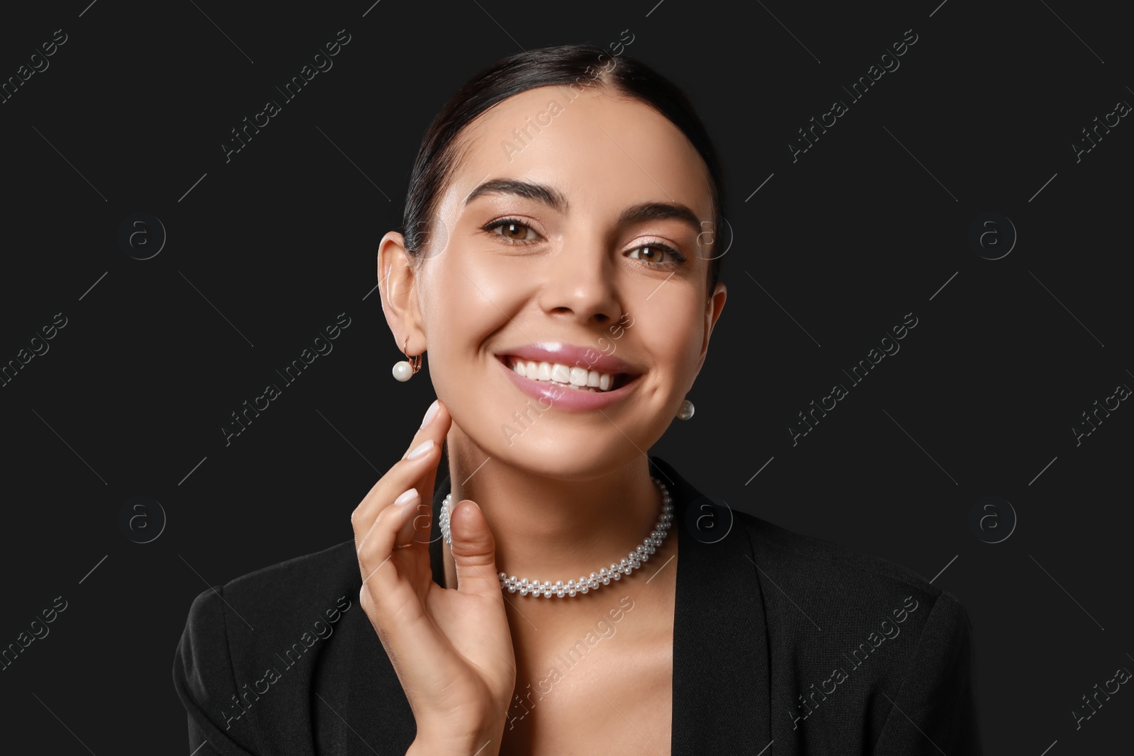 Photo of Young woman with elegant pearl jewelry on black background