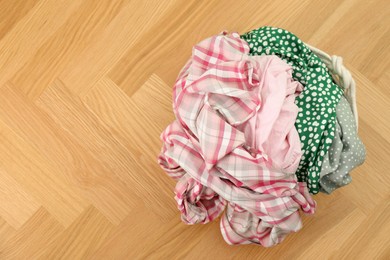 Laundry basket with clothes on floor, top view. Space for text