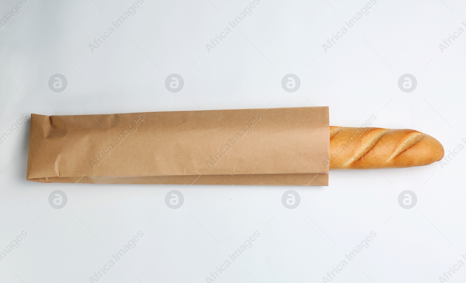 Photo of Paper bag with baguette on white background, top view. Space for design