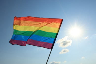 Photo of Bright LGBT flag fluttering against blue sky. Lesbian concept