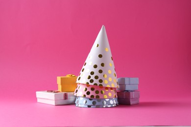 Party hats and gift boxes on pink background