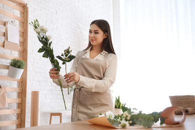 Photo of Florist making beautiful bouquet at table in workshop