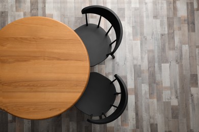 Wooden round table and black chairs indoors, top view. Space for text