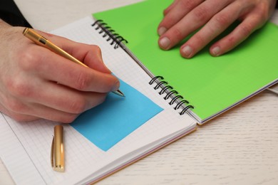 Photo of Man taking notes at white wooden table, closeup