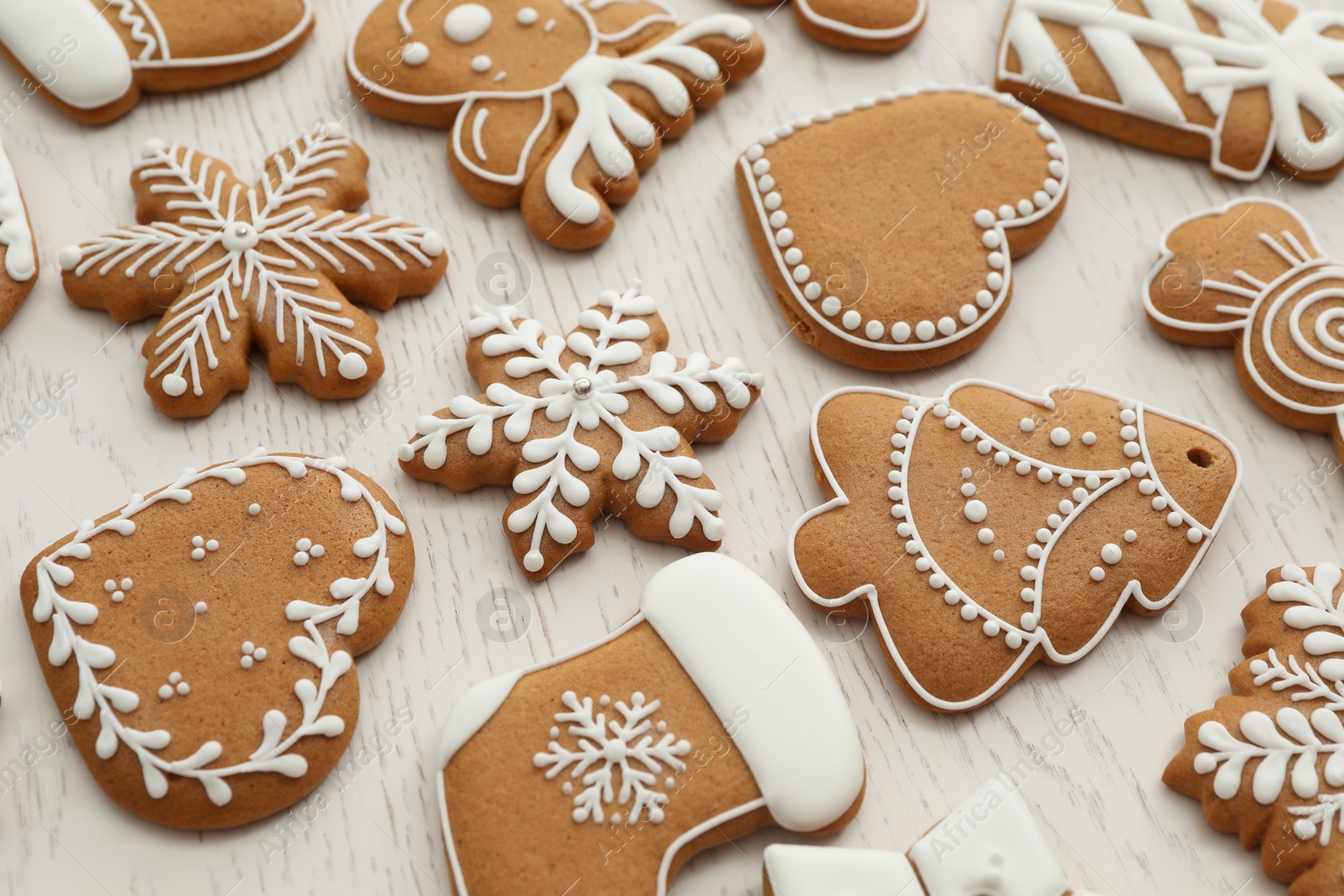 Photo of Different Christmas gingerbread cookies on white wooden table, closeup