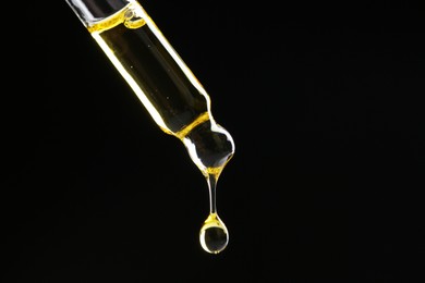 Photo of Dripping tincture from pipette on black background, closeup. Space for text