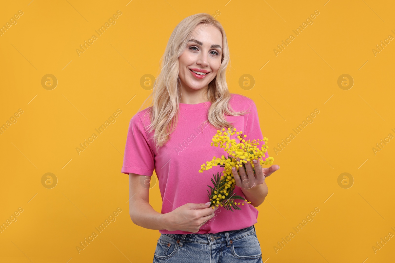 Photo of Happy young woman with beautiful bouquet on orange background