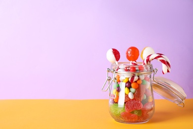 Photo of Different yummy candies on violet background. Space for text