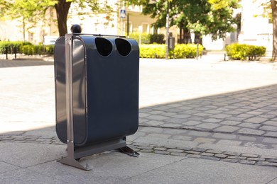 Photo of Modern metal recycling bin on city street. Space for text