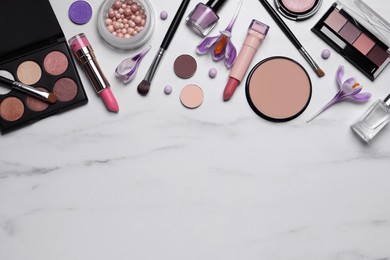 Flat lay composition with different makeup products and beautiful crocuses on white marble table, space for text