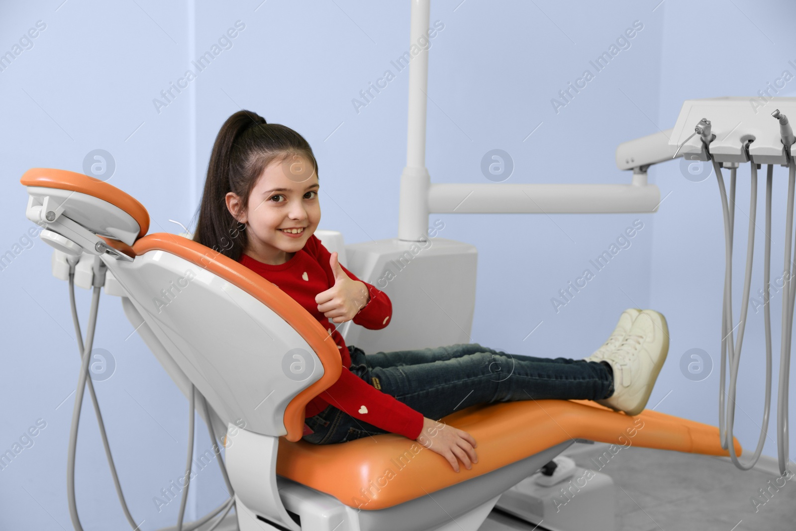 Photo of Happy little patient on dentist's chair in modern clinic