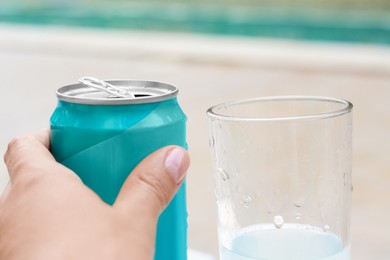 Photo of Woman holding aluminum can with drink on blurred background, closeup