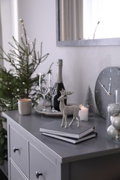 Photo of Christmas tree and decor on chest of drawers indoors. Interior design