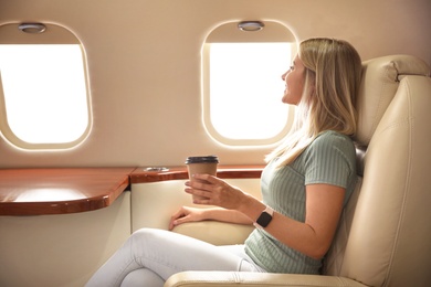 Image of Beautiful woman with paper cup on plane. Air travel