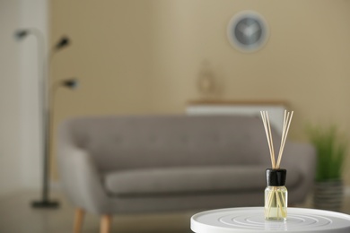 Aromatic reed air freshener on table against blurred background