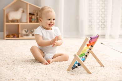 Photo of Children toys. Cute little boy and wooden abacus on rug at home