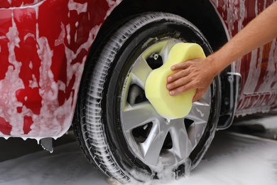 Man washing red auto with sponge at car wash, closeup