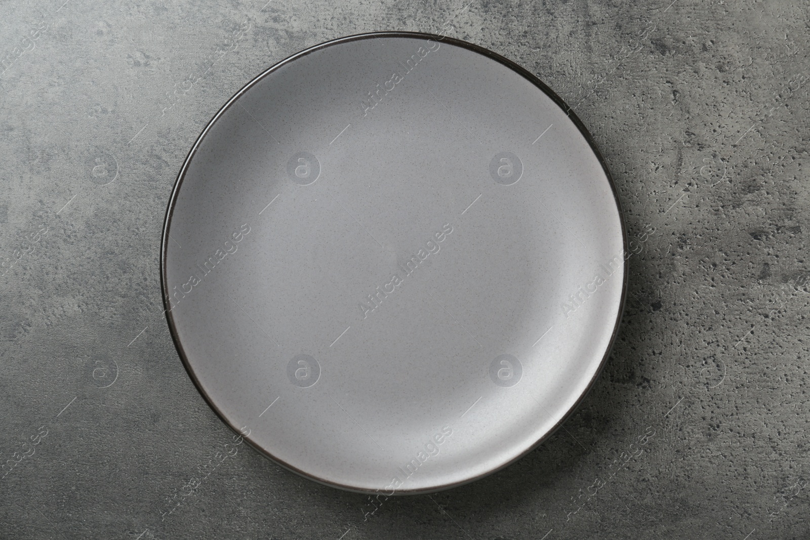 Photo of Empty ceramic plate on grey table, top view