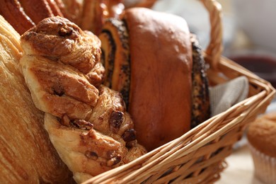 Photo of Different tasty freshly baked pastries in wicker basket, closeup