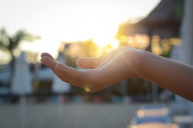 Girl holding her hand against sunlight on beach, closeup