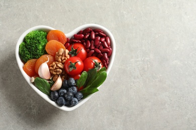Photo of Bowl with heart-healthy diet products on grey background, top view. Space for text