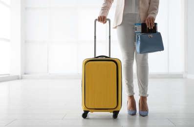 Businesswoman with yellow travel suitcase in airport