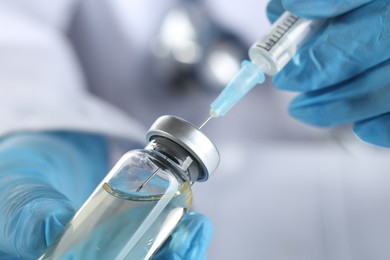 Doctor filling syringe with medication from glass vial, closeup